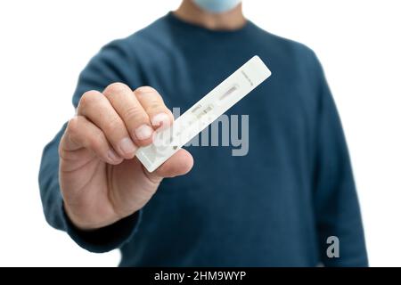 Mann zu Hause, der der Kamera seinen negativen Antigen-Covid-Test auf weißem Hintergrund zeigt. COVID-19-Konzept. Selektiver Fokus Stockfoto