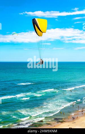 Gleitschirmflug über den Strand in der Stadt Torres in Rio Grande do Sul mit Meer und Horizont im Hintergrund Stockfoto