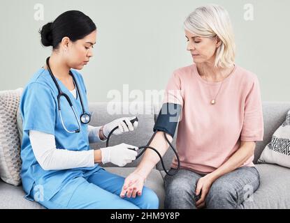 Lasst uns versuchen, die Ursache für Ihre Kopfschmerzen zu finden. Aufnahme einer Krankenschwester, die den Blutdruck ihrer Patienten überprüft. Stockfoto