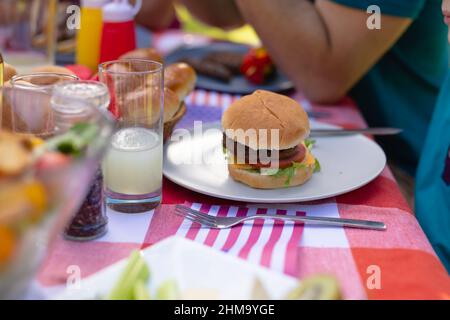 Nahaufnahme des Burgers, der auf dem Teller an Getränken auf dem Tisch serviert wird Stockfoto