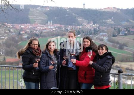 08. Februar 2022, Sachsen-Anhalt, Freyburg: Linda Trarbach (l-r), Deutsche Weinprinzessin, Sina Erdrich, Deutsche Weinkönigin, Luise Böhme, Weinkönigin der Region Saale-Unstrut, Saskia Teucke, Deutsche Weinprinzessin, und Antonia Odenthal, Freyburg Weinprinzessin, Stehen Sie am Unstrut River Valley mit der Stadt Freyburg im Hintergrund. Die Deutschen Weinprinzessinnen und die Deutsche Weinkönigin waren zu Gast im Weinanbaugebiet Sachsen-Anhalt anlässlich ihres ersten Besuches. Während ihrer Amtszeit reisen die Weinbotschafter in alle dreizehn Weinanbauregionen Deutschlands Stockfoto