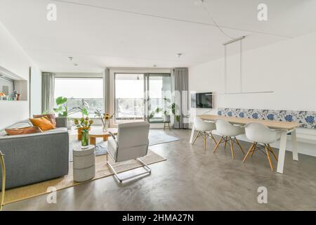 Komfortable Couch mit Kissen auf Teppich im geräumigen Wohnzimmer mit Dekorationen in der Nähe Esstisch zu Hause platziert Stockfoto