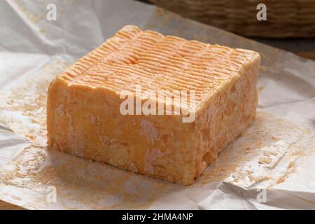 Einzelnes ganzes Stück Limburger oder Herve Käse mit starkem Geruch auf Packpapier Stockfoto