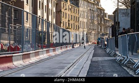 Leith, Edinburgh, Schottland, Großbritannien, 8th. Februar 2022. Straßenbahnen nach Newhaven Bau: Da sich das Großprojekt dem letzten Jahr nähert, die Arbeiten termingerecht und im Frühjahr 2023 im Rahmen des Budgets von £207,3m fertiggestellt werden, sind in Leith zahlreiche Straßen für den Verkehr gesperrt. Mehr als 60 % der Gleise wurden nun verlegt (2,8km) und 85 % der Umleitungen der Versorgungsunternehmen wurden durchgeführt. Im Bild: Die Trambahn auf der Constitution Street ist durch Barrieren eingezäunt Stockfoto