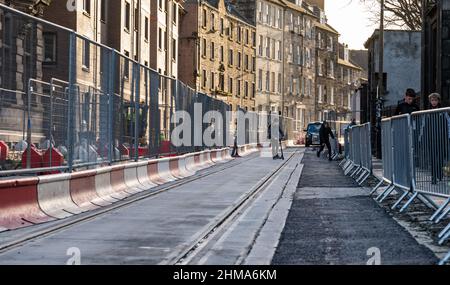 Leith, Edinburgh, Schottland, Großbritannien, 8th. Februar 2022. Straßenbahnen nach Newhaven Bau: Da sich das Großprojekt dem letzten Jahr nähert, die Arbeiten termingerecht und im Frühjahr 2023 im Rahmen des Budgets von £207,3m fertiggestellt werden, sind in Leith zahlreiche Straßen für den Verkehr gesperrt. Mehr als 60 % der Gleise wurden nun verlegt (2,8km) und 85 % der Umleitungen der Versorgungsunternehmen wurden durchgeführt. Im Bild: Die Trambahn auf der Constitution Street ist durch Barrieren eingezäunt Stockfoto