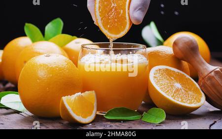 Gelbe Orangenfrüchte und frischer Orangensaft. Die frische Orange herausdrücken. Stockfoto