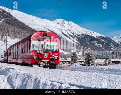 Cinuos-Chel, Schweiz - 3. Februar 2022: Roter Zug fährt zwischen Chur und Tirano in Italien und durchquert schneebedeckte Landschaft im Dorf Chin Stockfoto