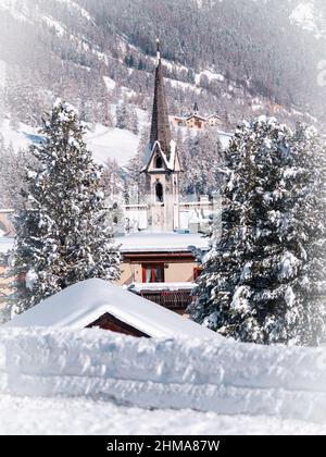 Cinuos-Chel, Schweiz - 3. Februar 2022: Winteransicht auf einem Glockenturm einer protestantisch reformierten Kirche in einem schneebedeckten Dorf von Cinuos Chel in eng Stockfoto