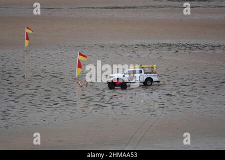 Rettungsschwimmer in einem RNLI 4 x 4 Fahrzeug an einem Strand in Großbritannien mit Warnflaggen Stockfoto