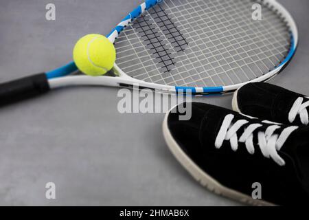 Tennisschläger und Ball auf grauem Hintergrund. Sportspiele. Die Meisterschaft Stockfoto