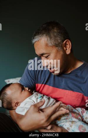 Mann hält Baby Mädchen im Schlafzimmer Stockfoto