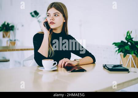 Nachdenkliche Frau, die im Café mit dem Handy spricht Stockfoto