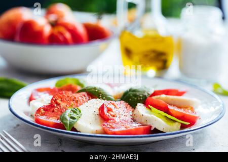 Frischer Caprese-Salat mit Mozzarella, Tomaten und frischem Basilikum mit Olivenöl darauf. Traditionelles italienisches Gericht, gesund, biologisch und leicht. Mittelmeer Stockfoto