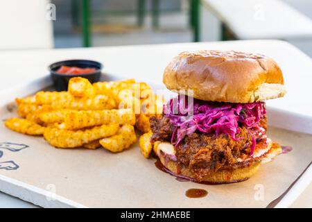 Ein Nashville Hot Chicken Sandwich mit lila Schlaw und Pommes frites Stockfoto