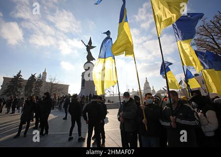 CHARKIW, UKRAINE - 5. FEBRUAR 2022 - Aktivisten halten ukrainische Flaggen am Unabhängigkeitsdenkmal auf dem Konstytutsii-Platz während des Einheits-Marsches in Kha fest Stockfoto