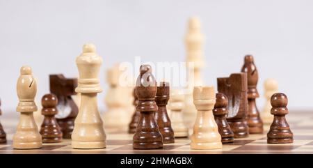 Schachfiguren auf einem Schachbrett während eines Spiels mit hellem Hintergrund Stockfoto