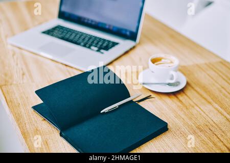 Notizbuch mit einer Tasse Kaffee und einem Netbook auf dem Tisch Stockfoto