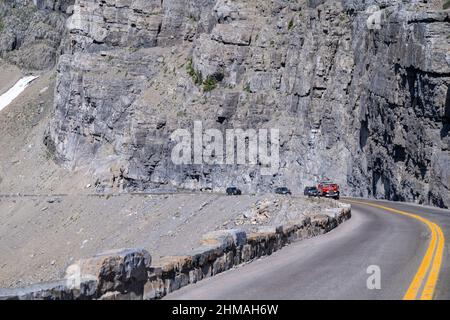 Montana, USA - 1. Juli 2021: Ein Tourbus mit roten Störern, gefüllt mit Touristen, macht sich auf den Weg zur Sun Road im Glacier National Park Stockfoto