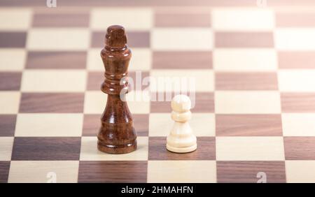 Kleines Schachbrett, das König auf einem leeren Schachbrett angreift. Geschäftskonzept Führung Stockfoto