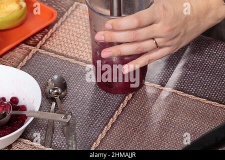 Mahlen Sie frische gefrorene Beeren in einem Mixer. Kochen Sie hausgemachte Gerichte aus frischen Beeren. Nahaufnahme. Stockfoto