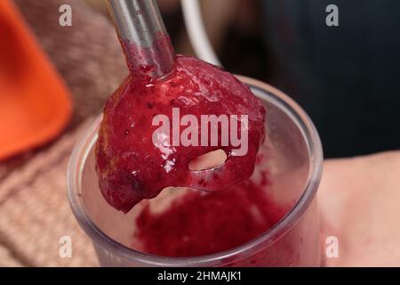 Mahlen Sie frische gefrorene Beeren in einem Mixer. Kochen Sie hausgemachte Gerichte aus frischen Beeren. Nahaufnahme. Stockfoto