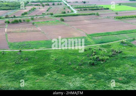 Schöne Landschaft mit frischem Pflügeland und Wiese. Frisch gepflügt und gesät Ackerland von oben, ordentlich in nicht-städtischen landwirtschaftlichen A angebaut Stockfoto