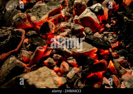 Hintergrund von brennender und glühender Glut. Schwelende Glut des Feuers. Flackern brennender Kohlen in der Nacht. Selektiver Fokus Stockfoto