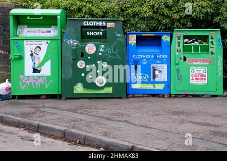 Eine Reihe von Metallbehältern am Straßenrand, die für gemeinnützige Spenden für Schuhe, Textilien und Kleidung zum Recycling bestimmt sind. Wird vom gemeinderat betrieben Stockfoto