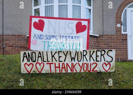 Ein Haushälter hat selbstgemachte Schilder in ihrem Vorgarten platziert. Die Zeichen zollen dem NHS, seinen Mitarbeitern und allen wichtigen Mitarbeitern Tribut und danken ihnen Stockfoto