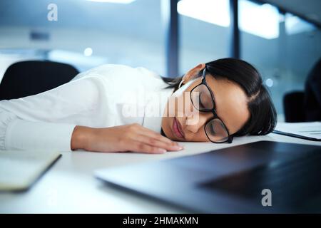 Nur meine Augen ein wenig ruhen. Aufnahme einer jungen Geschäftsfrau, die an ihrem Schreibtisch ein Nickerchen machte. Stockfoto