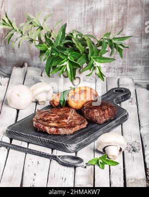 Auswahl an mittelseltenen Steaks, geschnitten mit Messer mit Kartoffelkeilen als Beilage. Kochen im Freien, und tolle Schnitte von Sirloin, Filet. Grill Stockfoto