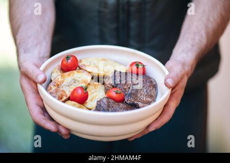 Auswahl an mittelseltenen Steaks, geschnitten mit Messer mit Kartoffelkeilen als Beilage. Kochen im Freien, und tolle Schnitte von Sirloin, Filet. Grill Stockfoto