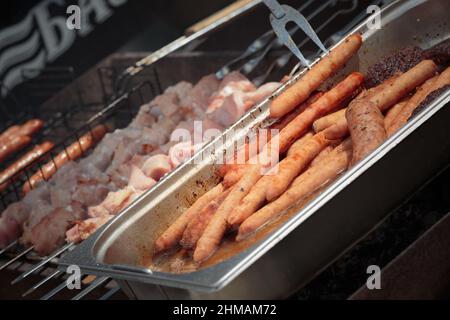 Vorbereitung von Shish Kebab und Würstchen auf Holzkohlegrill im Freien. Nahaufnahme. Stockfoto