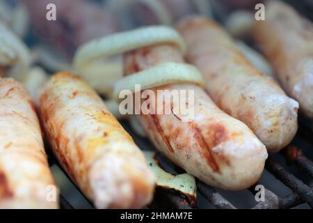 Köstliche gegrillte Würstchen und Zwiebelringe. Nahaufnahme. Stockfoto