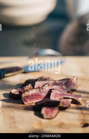 Auswahl an mittelseltenen Steaks, geschnitten mit Messer mit Kartoffelkeilen als Beilage. Kochen im Freien, und tolle Schnitte von Sirloin, Filet. Grill Stockfoto