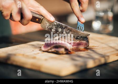 Auswahl an mittelseltenen Steaks, geschnitten mit Messer mit Kartoffelkeilen als Beilage. Kochen im Freien, und tolle Schnitte von Sirloin, Filet. Grill Stockfoto