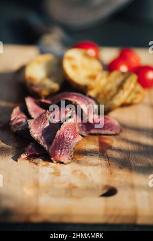 Auswahl an mittelseltenen Steaks, geschnitten mit Messer mit Kartoffelkeilen als Beilage. Kochen im Freien, und tolle Schnitte von Sirloin, Filet. Grill Stockfoto