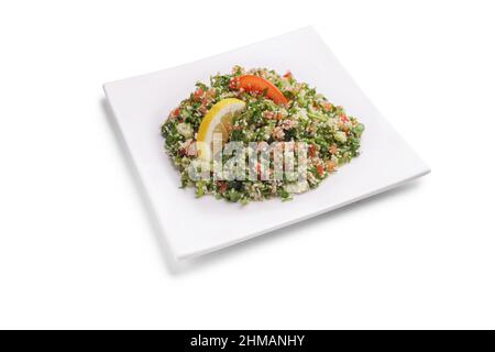 Arabisches Gericht Tabbouleh auf einem quadratischen weißen Teller isoliert auf weißem Hintergrund Stockfoto