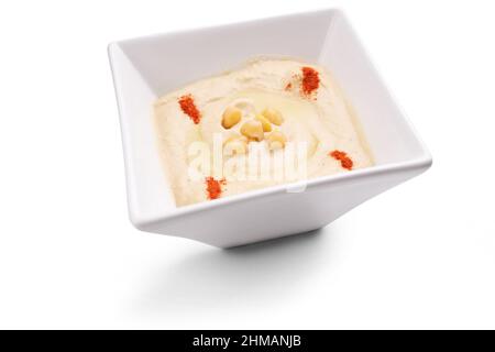 Arabisches Dip Hummus in einer weißen Schüssel mit Kichererbsen und Paprika auf weißem Hintergrund isoliert dekoriert Stockfoto