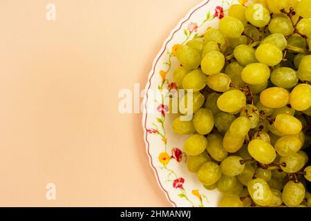 Reife weiße Bio-Trauben auf einem Teller auf türkisfarbenem Hintergrund, Obst, gesunde Ernährung, Vegetarismus. Draufsicht. Veganes Essen, Kopierraum Stockfoto