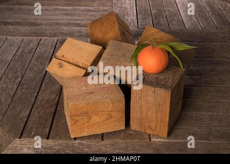 Stillleben mit Mandarine und Holzwürfeln. Es befindet sich auf einer hölzernen Oberfläche. Nahaufnahme. Stockfoto