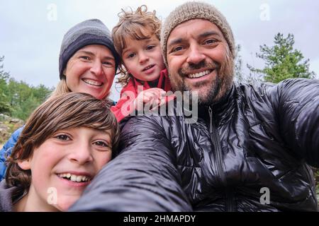 Eine glückliche Familie entspannt sich und macht Selfie in den Bergen Stockfoto
