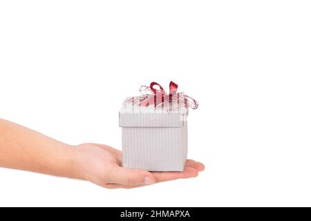 Geschenkbox mit roter Schleife in der Hand. Isoliert auf weißem Hintergrund. Nahaufnahme. Stockfoto