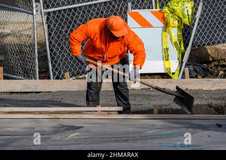 Betonbauunternehmer, der einen Gehweg, eine Bordsteinkante und eine Sturmabflussrinne auf einer neuen Hauskonstruktion installiert. Stockfoto