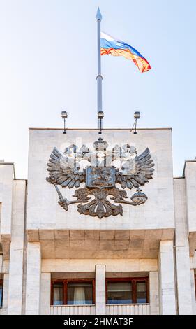 Das russische Wappen und die Staatsflagge auf dem Verwaltungsgebäude Stockfoto