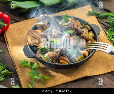 Garen Sie einfach dampfende Steinpilze in der Pfanne auf dem Holztisch. Draufsicht. Stockfoto