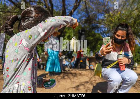 Una Niña observa un pez lobina de la pesca deportiva y recreativa que practican las familias hermosillenses en el humedal del Parque La Sauceda, su madre le Toma una fotografia con su telefono inteligente, Ein Mädchen beobachtet einen Barschfisch aus dem Sport- und Freizeitfischen, das Familien aus Hermosillo im Feuchtgebiet des La Sauceda Parks praktizieren, ihre Mutter fotografiert ihn mit ihrem Smartphone, Anzuelo, Fischhaken, Am 5. Februar 2022 in Hermosillo, Mexiko, anlässlich des Welttages der Feuchtgebiete zur Förderung der Erhaltung und Erhaltung der biologischen Vielfalt der Ökosysteme. (Foto von Luis Gutierrez Norte Photo/) Stockfoto