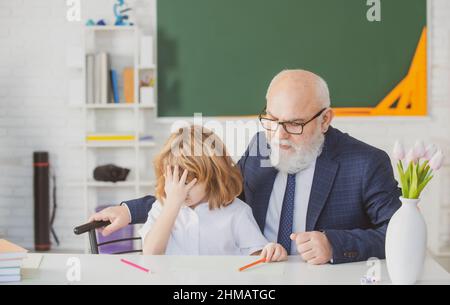 Porträt von Großvater und traurigen Enkel Schüler mit Problem im Klassenzimmer in der Schule. Stockfoto