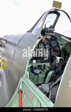 Cockpit eines Spitfire V Kampfflugzeugs aus dem zweiten Weltkrieg. Instrumententafel, Steuersäule, Pistolenknopf, Auslöser. Zifferblätter, Anzeigen. Gun Visier. G-MKVB Stockfoto