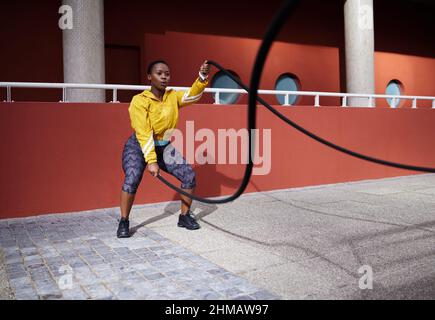 Schmerz in Kraft verwandeln. Aufnahme einer jungen Frau mit Kampfseilen vor städtischem Hintergrund. Stockfoto